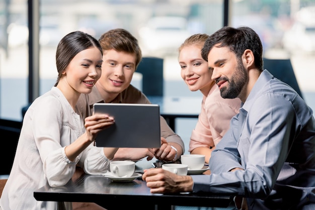 Equipe de negócios em reunião para discutir projeto com tablet digital no café, conceito de almoço de negócios