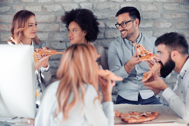 Equipe de negócios feliz comendo pizza no escritório