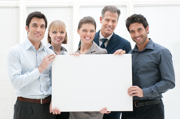 Equipe de negócios feliz e sorridente segurando um cartaz em branco pronto para seu texto ou produto