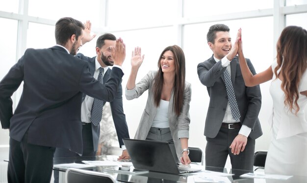 Equipe de negócios feliz em pé perto da mesa do escritório