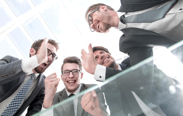 Equipe de negócios feliz vista inferior em pé perto da mesa do escritório