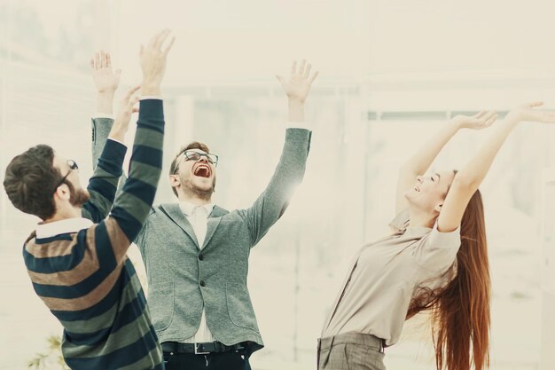 Equipe de negócios jubilosa em pé em um círculo, mãos ao alto em exultação de sucesso. A foto tem um espaço vazio para o seu texto.