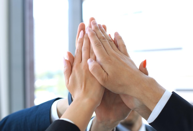 Equipe de negócios, juntando as mãos em pé no escritório.