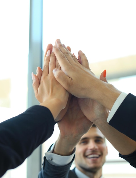 Equipe de negócios juntando as mãos em pé no escritório