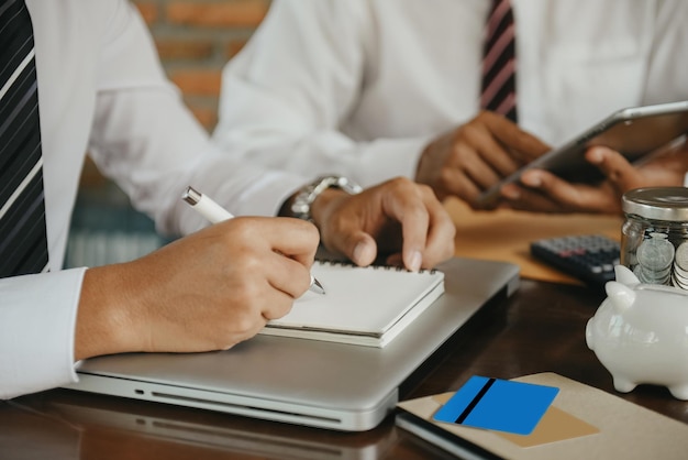 Equipe de negócios masculina usa um laptop e toma notas no notebook na mesa do escritório