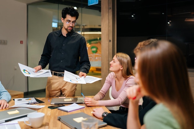 Equipe de negócios multiétnica positiva com líder masculino discutindo brainstorming de projeto no escritório falando rindo Equipe de treinamento de professores corporativos