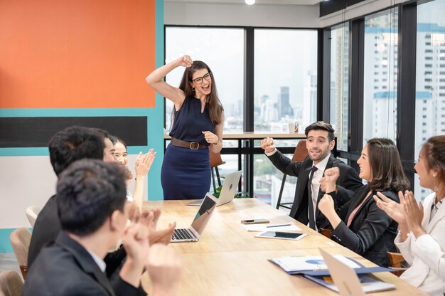 Equipe de negócios multiétnica torcendo e aplaudindo o sucesso da empresa em um escritório moderno