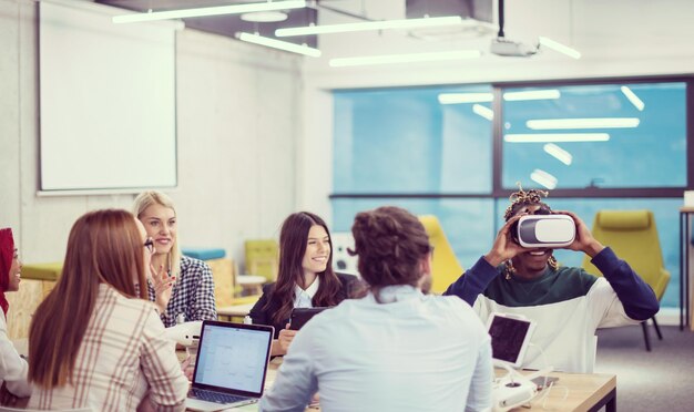 Equipe de negócios multiétnica usando fone de ouvido de realidade virtual na reunião de escritório Reunião de desenvolvedores com simulador de realidade virtual ao redor da mesa no escritório criativo.