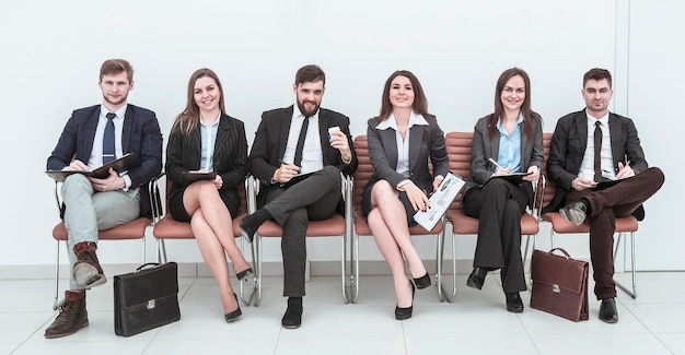 Equipe de negócios trabalhando com documentos antes da sessão de trabalho, sentada em cadeiras de escritório em frente à sala de conferências