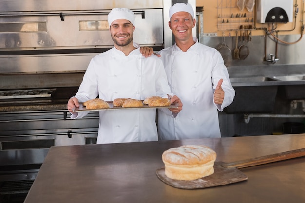 Equipe de padeiros sorrindo na câmera com bandejas de croissants