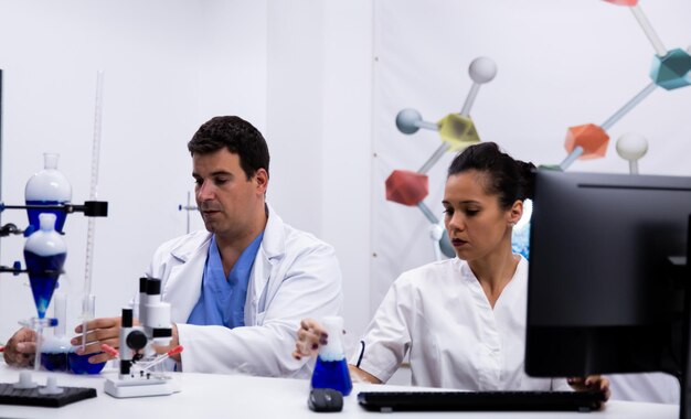 Equipe de pesquisadores vestindo casaco em laboratório de pesquisa moderno. Pc em laboratório.