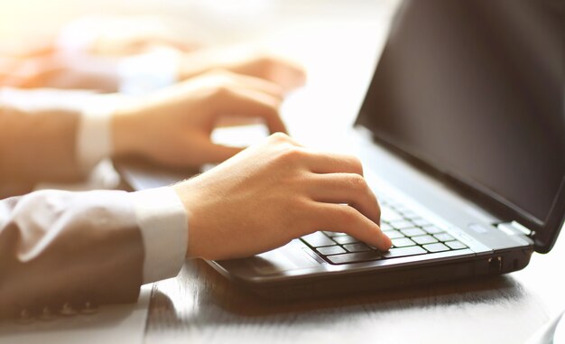 Equipe de pessoas digitando em um laptop moderno no escritório