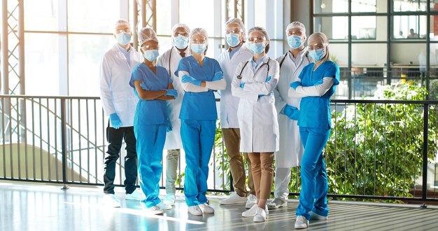 Equipe de raças mistas de médicos profissionais masculinos e femininos no hospital. Interior. Grupo internacional de médicos com máscaras médicas. Médicos multiétnicos em batas e uniformes na clínica.