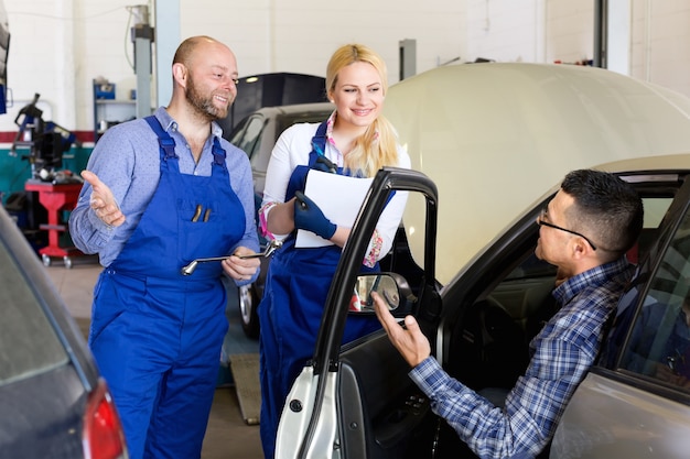 Equipe de serviço e motorista perto do carro