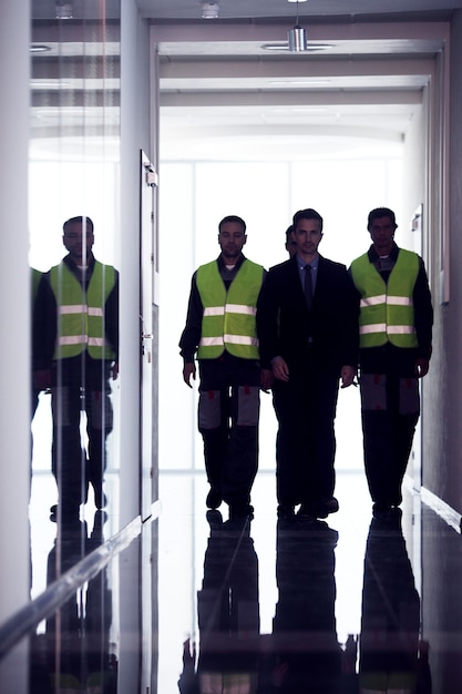 Equipe de trabalhadores e gerente caminhando no corredor da fábrica