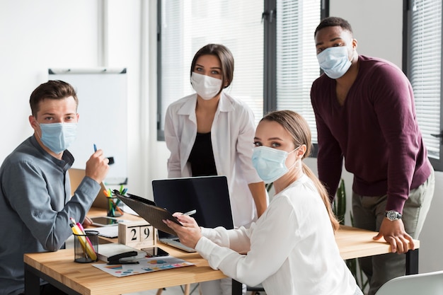Equipe de trabalho no escritório durante pandemia usando máscaras faciais