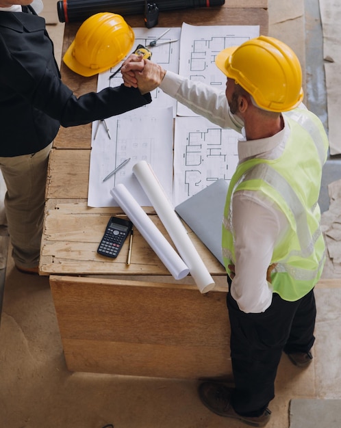 Equipe diversificada de especialistas usa computador tablet no projeto de construção de imóveis com engenheiro civil, arquiteto, investidor comercial e trabalhador em geral, discutindo detalhes do plano