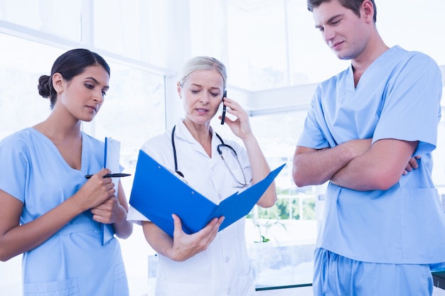 Equipe dos médicos que olham a pasta