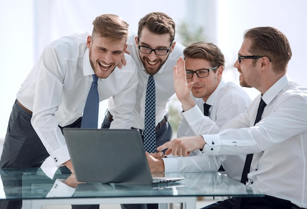 Equipe feliz e animada olhando para a inicialização da tela do laptop