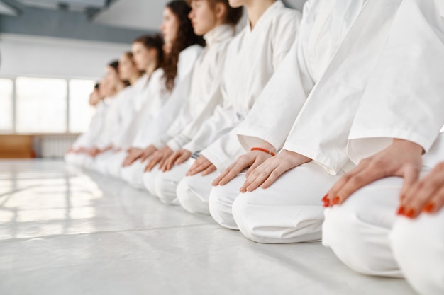 Equipe jovem em uniforme de artes marciais branco sentado no chão no ginásio