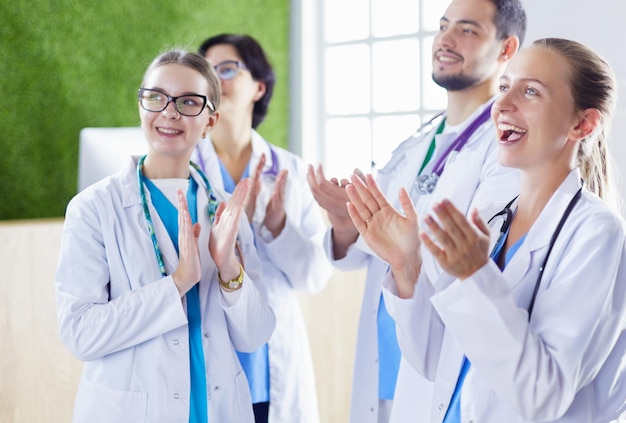 Foto equipe médica feliz composta por médicos homens e mulheres sorrindo amplamente e dando um polegar para cima de sucesso e esperança