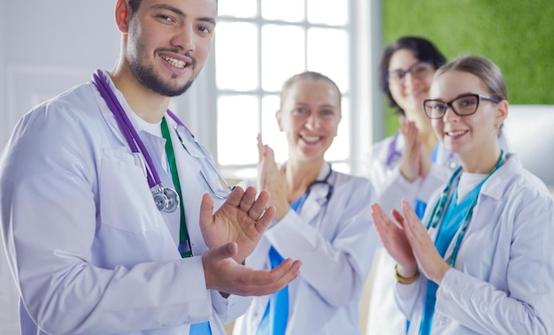 Equipe médica feliz composta por médicos homens e mulheres sorrindo amplamente e dando um polegar para cima de sucesso e esperança