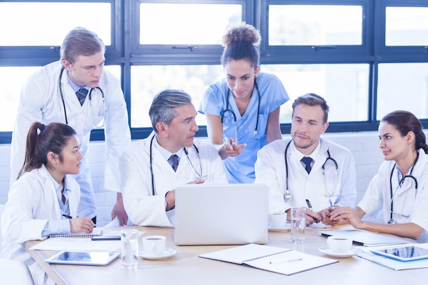 Equipe médica olhando para laptop e tendo uma discussão na sala de conferências