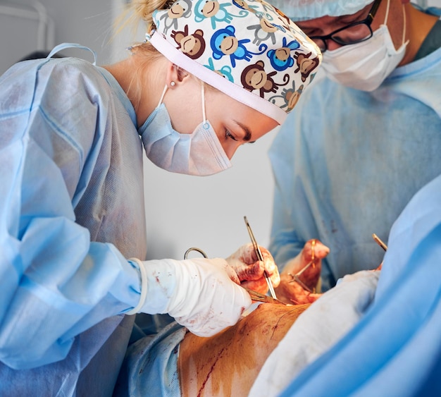 Equipe médica realizando cirurgia de abdominoplastia na sala de cirurgia