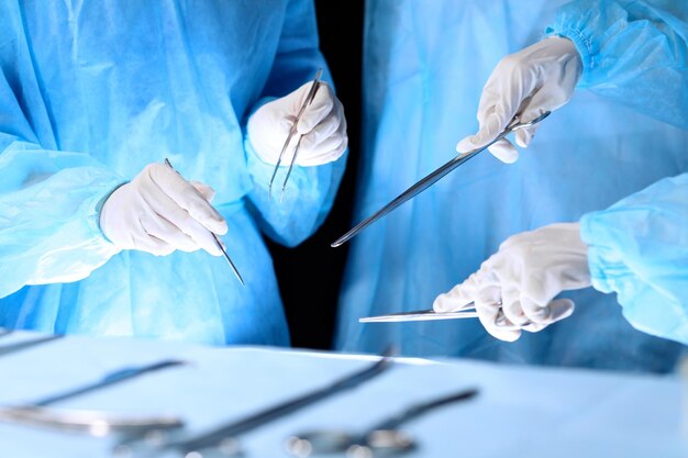 Equipe médica realizando operação. Grupo de cirurgião está trabalhando na sala de cirurgia em tons de azul.