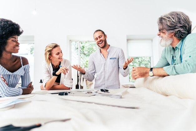 Equipe multiétnica de designers de moda trabalhando em uma oficina de criação de roupas - Grupo multirracial de estilistas, estilistas e costureiras trabalhando em uma nova coleção