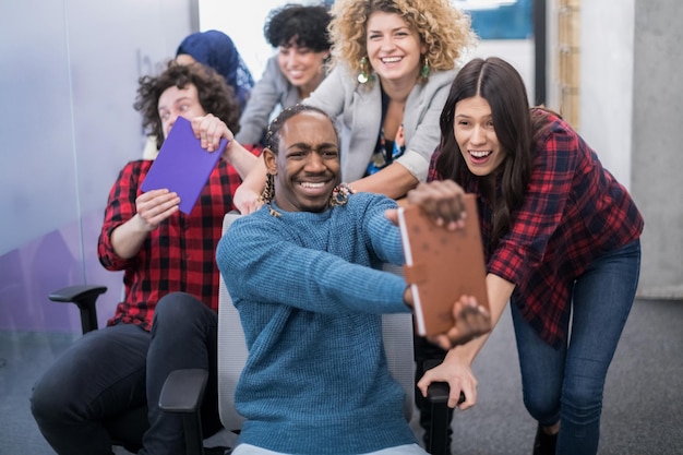 equipe multiétnica de empresa de startups de desenvolvedores de software se divertindo enquanto corria em cadeiras de escritório, funcionários diversos animados rindo desfrutando de atividades engraçadas no intervalo do trabalho, funcionários criativos e amigáveis.