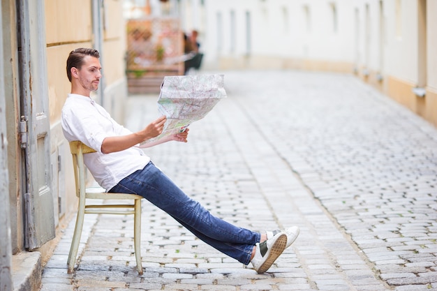 Equipe o turista com um mapa da cidade e trouxa na rua de europa.