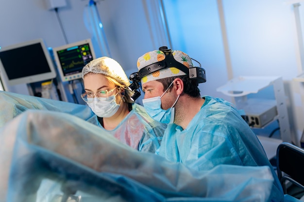 Equipe profissional de cirurgiões proctologista realizando operação usando dispositivos médicos especiais na sala de cirurgia do hospital Conceito cirúrgico urgente