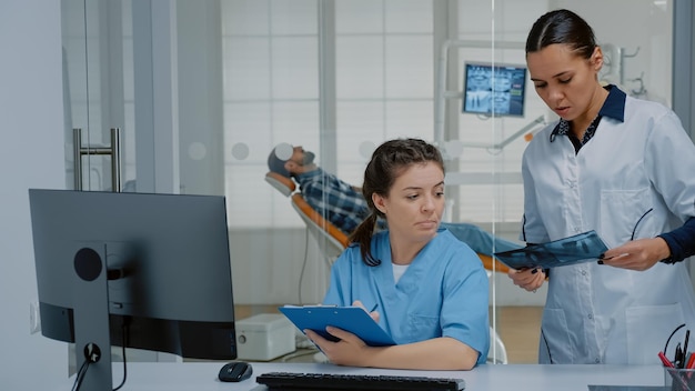 Equipe profissional de dentista e enfermeira que trabalha no cuidado dos dentes do paciente, usando varredura de raio-x odontológico, equipamento de estomatologia e computador na clínica odontológica. ortodontistas com ferramentas médicas