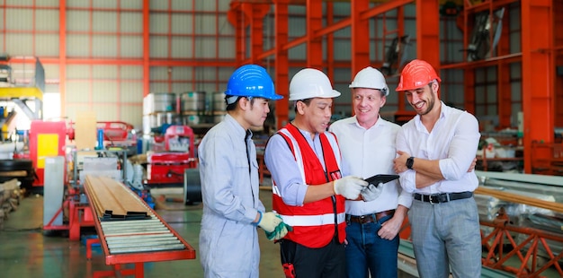 Equipe profissional de engenheiro mecânico trabalhando em computador pessoal na fábrica de fabricação industrial de chapas de metal Qualidade do produto Trabalhador de inspeção em capacete de segurança na fábrica industrial