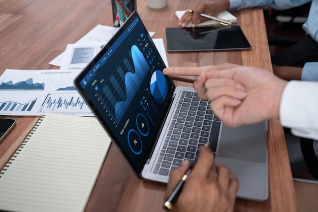 El equipo de analistas multirracial utiliza el software BI Fintech para analizar datos financieros en la mesa de reuniones Visualización de datos del panel financiero en la pantalla del portátil con gráfico analizado para indicación de marketing Concord