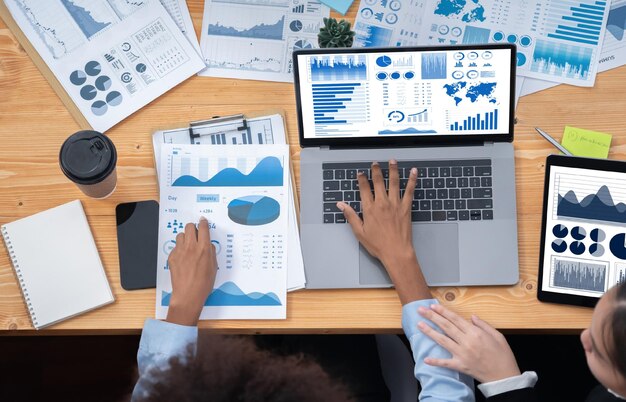 El equipo de analistas multirraciales utiliza el software BI Fintech para analizar los datos financieros en la reunión Vista superior de la pantalla de datos del tablero de finanzas en la pantalla del portátil con el gráfico analizado para la indicación de marketing Concord