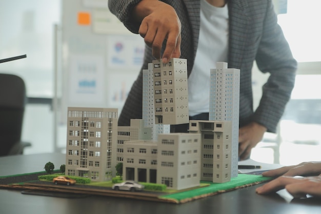 Equipo de arquitectos y empresarios discutiendo y intercambiando ideas sobre la modificación del plano de planta para el proyecto de inversión inmobiliaria y desarrollo de viviendas
