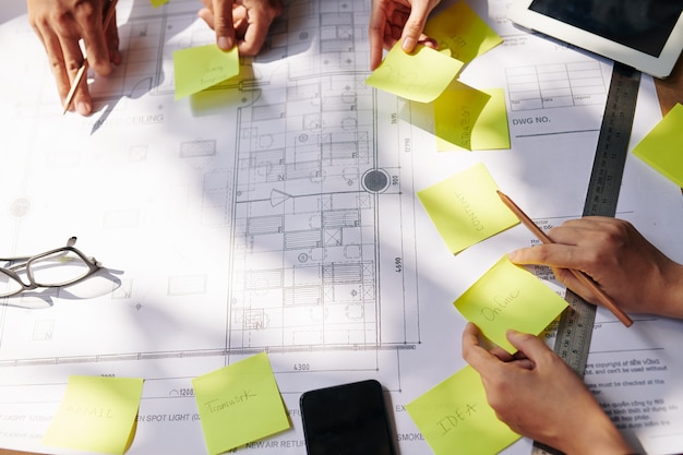 Foto equipo de arquitectos y gerentes pegando notas sobre planos de construcción al planificar el trabajo