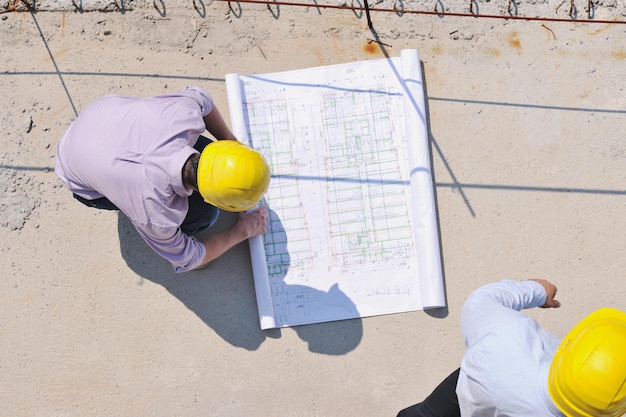 Equipo de arquitectos en grupo en el sitio de construcción revisa documentos y flujo de trabajo comercial