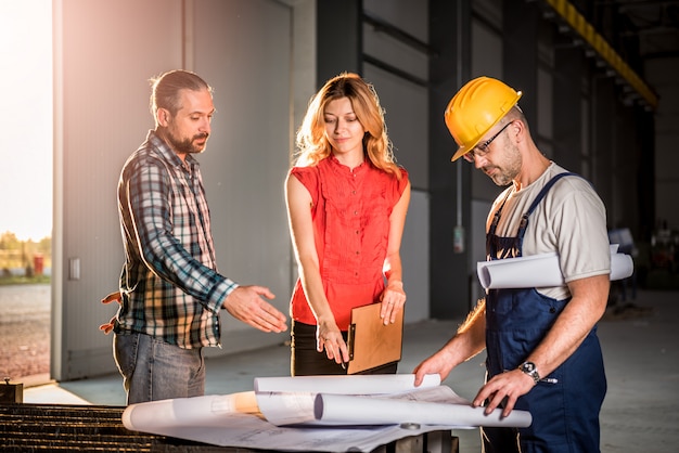 Equipo de arquitectos revisando el plano en el sitio de trabajo