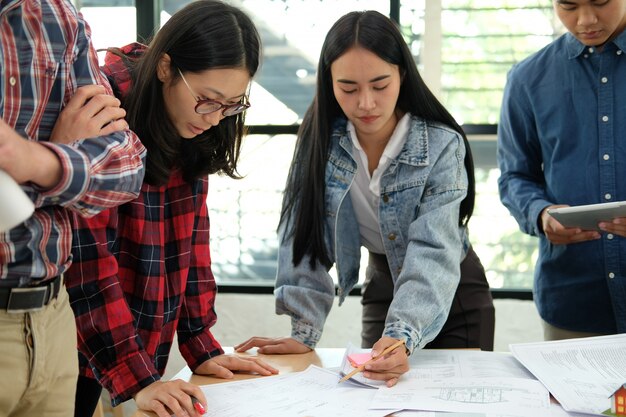 Equipo de arquitectos trabajando discutiendo sobre el plano de la casa del proyecto inmobiliario en reunión