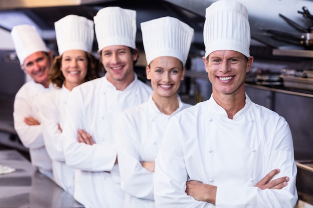 Equipo de chefs felices parados juntos en la cocina comercial