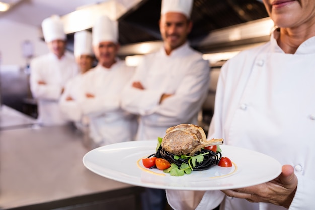 Equipo de chefs con uno que presenta un plato