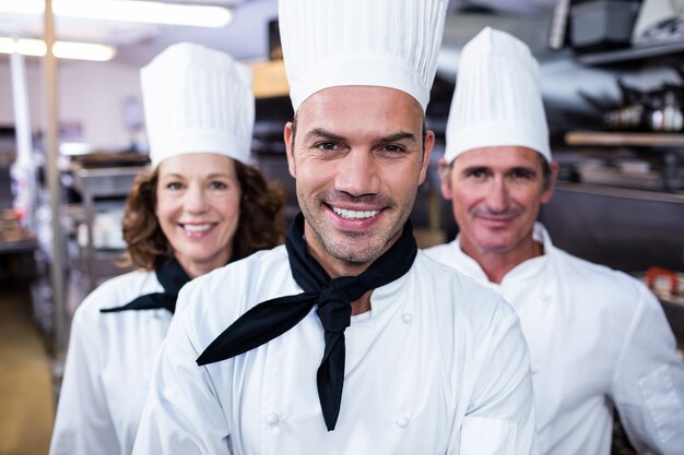 Foto equipo de chefs sonriendo en cocina comercial