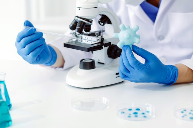 Equipo científico de investigación bioquímica que trabaja con microscopio para el desarrollo de vacunas contra el coronavirus en el enfoque selectivo del laboratorio de investigación farmacéutica