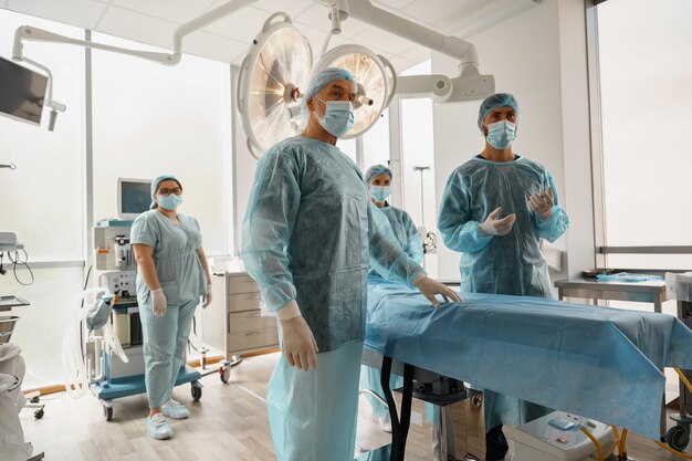 Equipo de cirujanos en la sala de operaciones listo para la cirugía en la clínica esperando al paciente