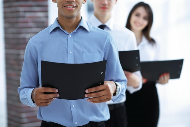 Equipo de Closeupbusiness con carpetas de negocios de pie el uno para el otro