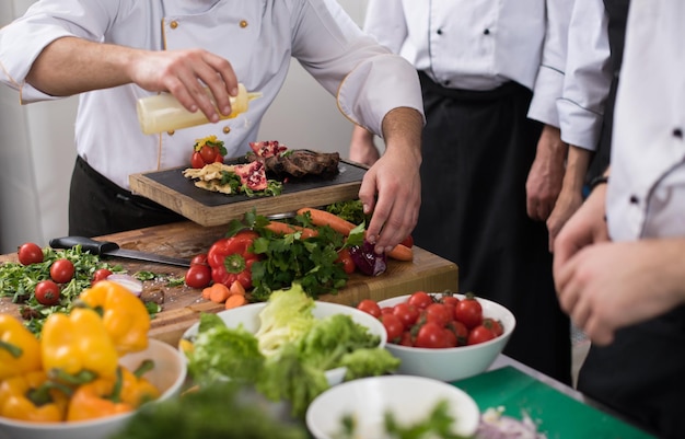 Equipo de cocineros y chefs profesionales que preparan la comida en la concurrida cocina de un hotel o restaurante