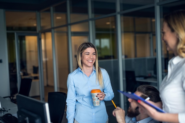 Equipo de colegas tomando café y trabajando en la oficina.